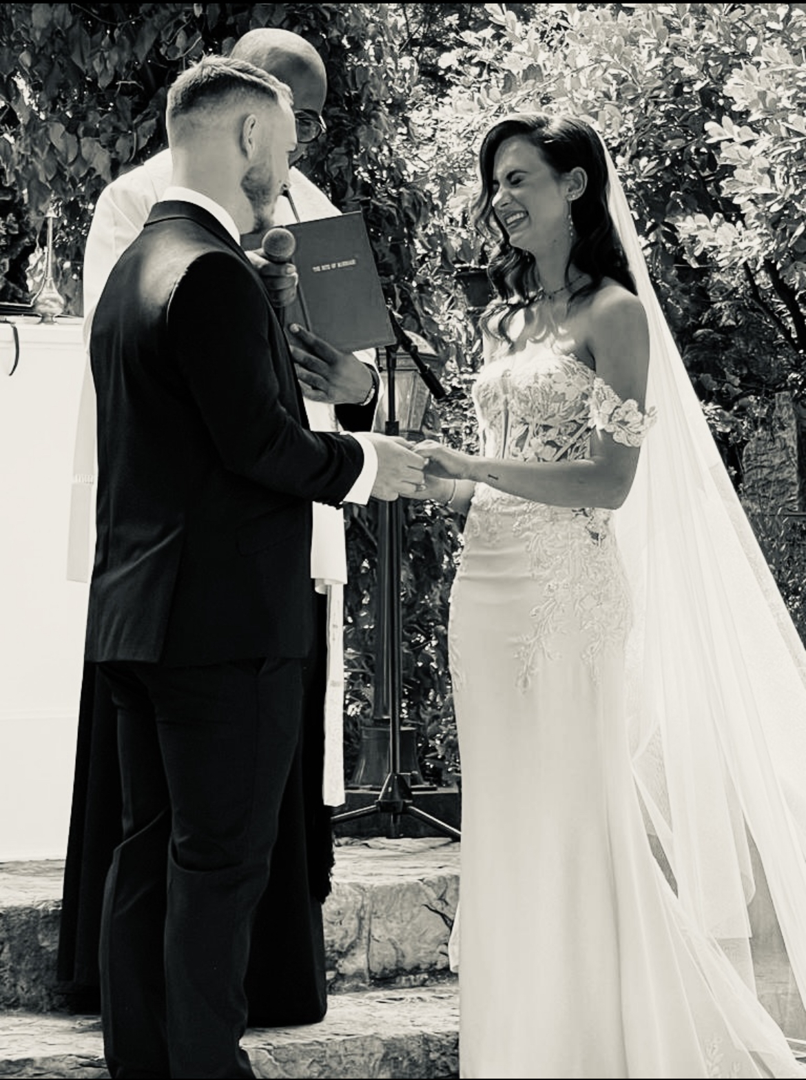 Black and white photograph of Jason and Savanna Knowles exchanging rings during the ceremony