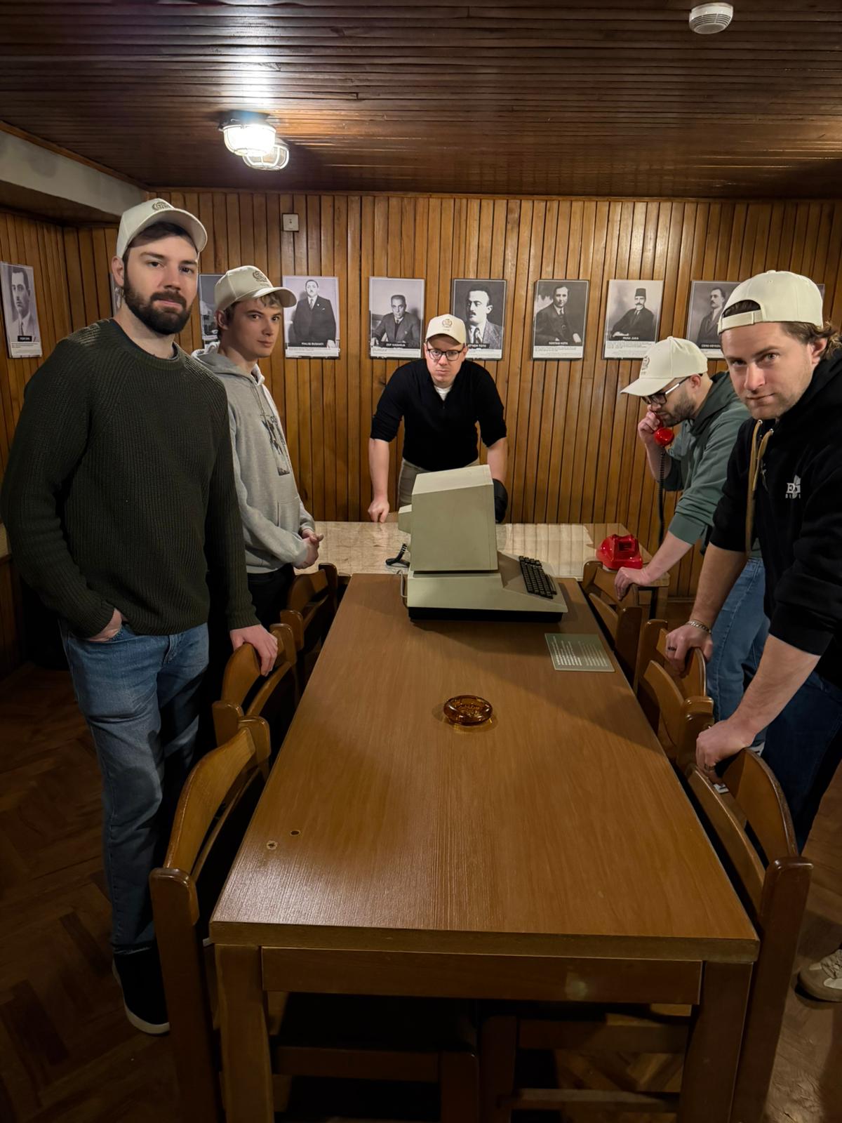 Executive Committee members around a table with period computer equipment in a wood-panelled room