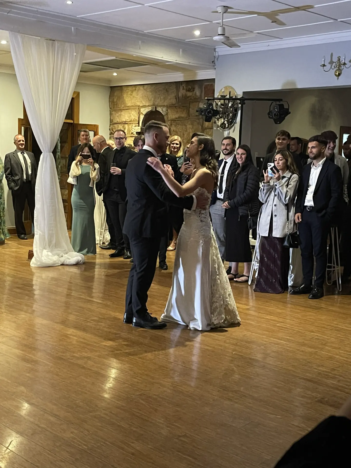 Jason and Savanna sharing their first dance as guests look on