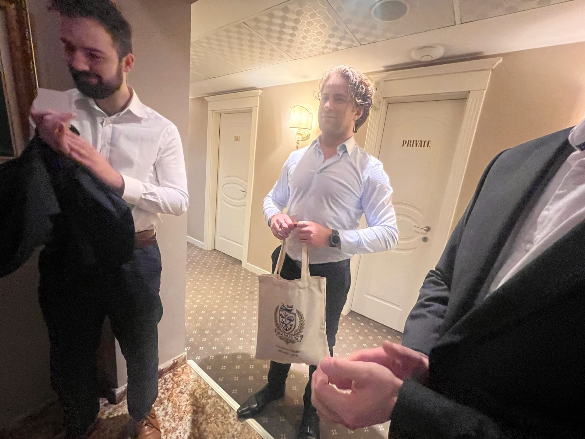 An executive in a hotel corridor holding a PBI-branded tote bag
