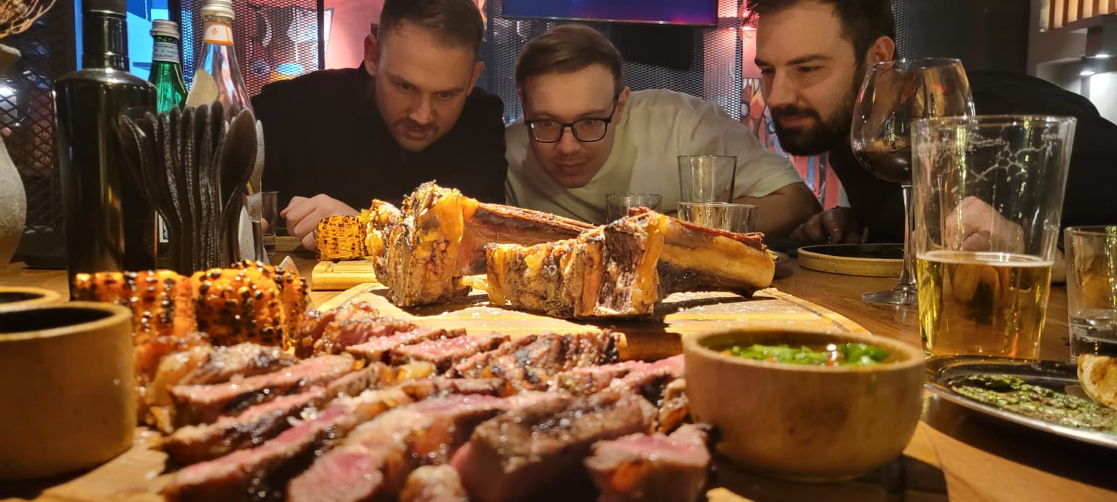 Three executives examining a large platter of grilled meat